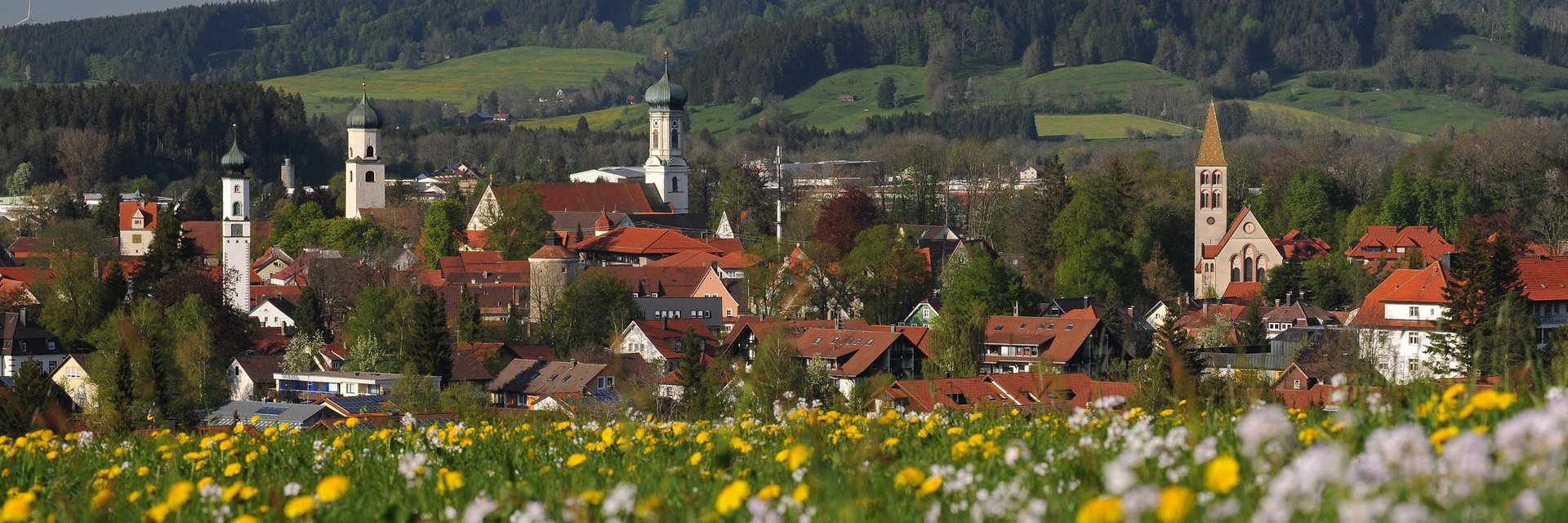 Die Stadt Isny mit vier Kirchtürmen und Hügel im Hintergrund